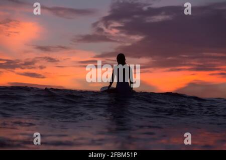 Donna surfista seduto sulla tavola da surf in mare durante la vacanza Foto Stock