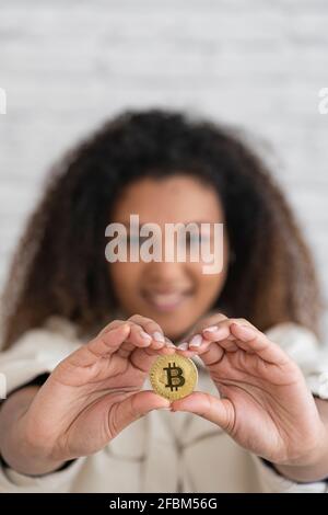 Sorridente giovane donna che tiene il bitcoin d'oro Foto Stock