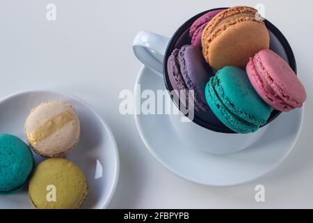 Tazza bianca piena di macaron colorati su sfondo chiaro. Spazio di copia. Messa a fuoco selettiva. Foto Stock
