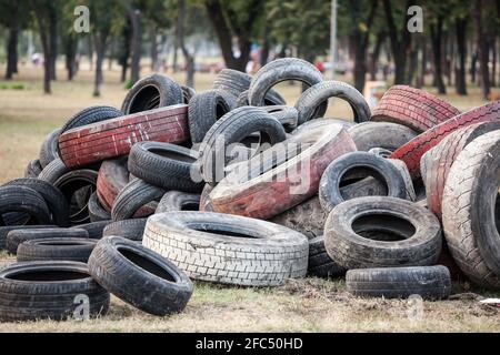 Sfocatura selettiva su pile di pneumatici usati e vecchi di seconda mano in un garage discarica junkyard. Questi pneumatici sono stati utilizzati per le automobili e altri veicoli più grandi, prima Foto Stock