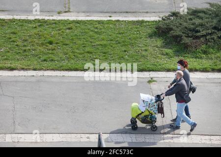 BELGRADO, SERBIA - 27 MARZO 2021: Famiglia europea, padre e madre, e il loro bambino, in passeggino, a piedi indossare maschera di protezione equipaggiamento Foto Stock