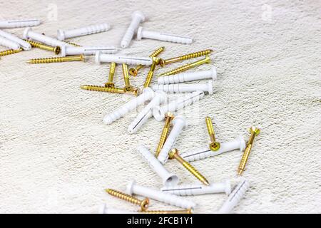 Molti tasselli in acciaio e plastica per la riparazione su fondo in cemento grigio chiaro con spazio di copia. Fai da te, miglioramento della casa e concetto di costruzione della casa. Foto Stock