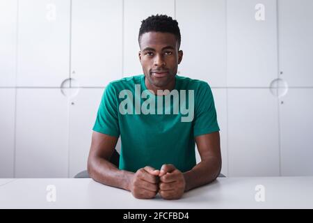 Felice uomo d'affari africano americen seduto alla scrivania mentre ha un videochiama sorridendo Foto Stock