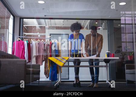 Diversi stilisti maschili e femminili al lavoro discutono e esaminare gli schizzi Foto Stock