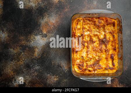 Lasagna italiana con salsa bolognese di pomodoro e carne di manzo macinata, in teglia, su fondo vecchio rustico scuro, vista dall'alto, piatto, con copy spac Foto Stock