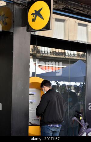 Vendrell, Spagna. 24 Apr 2021. Un uomo ritira denaro da un bancomat CaixaBank a El Vendrell. Il management di CaixaBank ha proposto ai sindacati un adeguamento del 18.7% della forza lavoro, cioè 8,291 persone. Questa riduzione dell'occupazione significherebbe che la nuova banca, unita a Bankia, sarebbe stata in grado di passare dagli attuali 44,400 lavoratori a 36,109. Le rettifiche riguardano CaixaBank Espà, non le controllate del gruppo all'estero. Credit: SOPA Images Limited/Alamy Live News Foto Stock