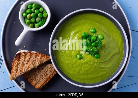 Zuppa di crema di piselli freschi fatti in casa con menta e pane tostato. Foto Stock
