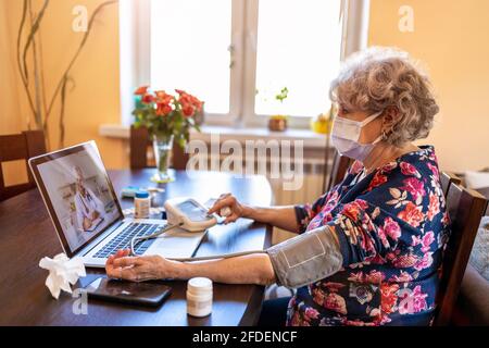 Donna anziana che consulta con un medico sul suo laptop Foto Stock