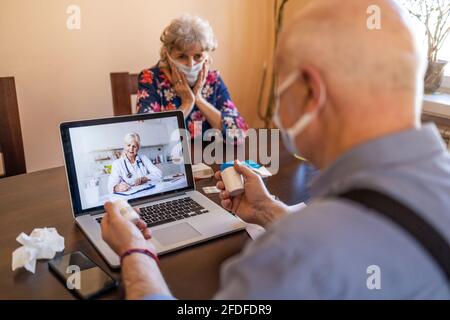 Consulenza di coppia senior con un medico sul computer portatile a casa Foto Stock