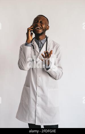 Immagine in primo piano di un giovane medico afroamericano in piedi in bianco uniforme su sfondo bianco Foto Stock