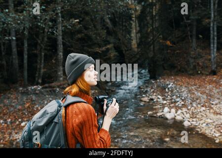 donna con una macchina fotografica vicino a uno stagno in montagna sulla natura e gli alberi Foto Stock