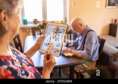 Consulenza di coppia senior con un medico su tablet digitale Foto Stock