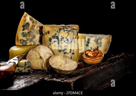 Vari formaggi gourmet di lusso assortiti su una tavola di legno su sfondo scuro. Vari tipi di formaggio: Duro e morbido con muffa. Immagine chiave bassa. COP Foto Stock