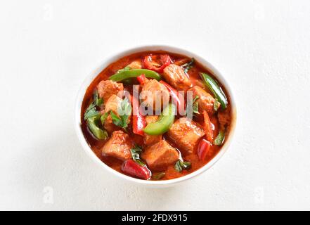 Primo piano vista del curry di pollo rosso in stile thailandese con verdure in ciotola su sfondo chiaro con spazio libero per il testo. Foto Stock