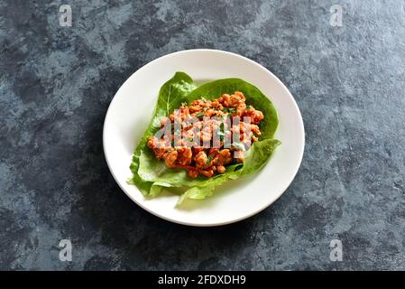 Primo piano vista di involtini di lattuga di carne tritata asiatici su sfondo di pietra blu. Foto Stock