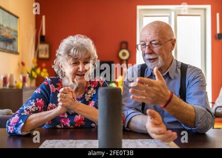 Una coppia senior entusiasta che utilizza un assistente virtuale a casa Foto Stock