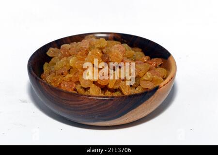 Uvetta secca in una ciotola di legno marrone isolata su fondo bianco, uvetta iraniana Foto Stock