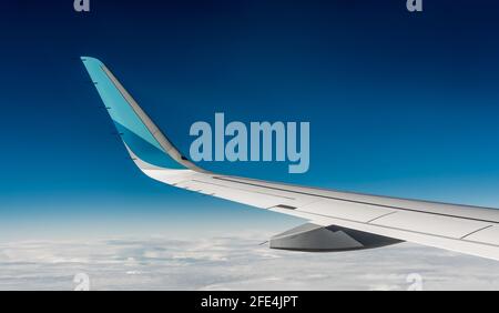 Ala di aereo. Vista dal sedile dei finestrini durante il volo in aereo. Cielo blu con tenui nuvole bianche Foto Stock