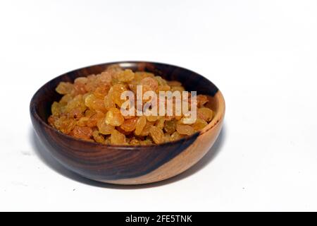 Uvetta secca in una ciotola di legno marrone isolata su fondo bianco, uvetta iraniana Foto Stock