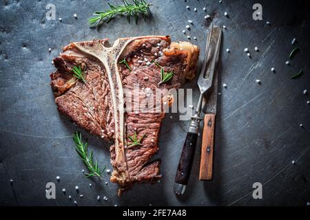 Bistecca di ossa ben fatta. Deliziosa e fresca bistecca di ossa con erbe e sale. Foto Stock