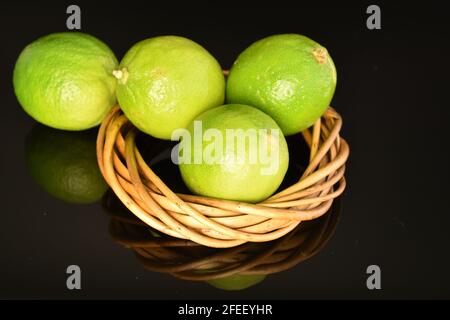 Un po' di calce verde, gustosa con una corona di ramoscelli, primo piano, su sfondo nero. Foto Stock