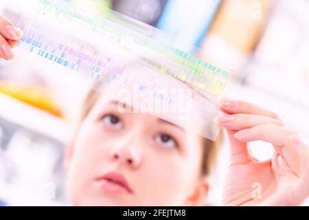 La giovane donna esamina un quadro di spettroscopia in una fisica quantistica laboratorio Foto Stock