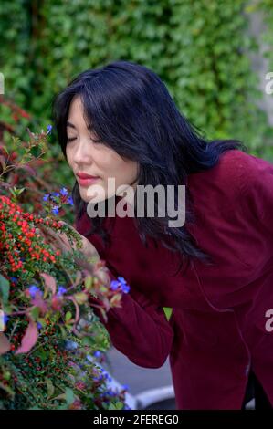 Bella donna cinese con lunghi capelli neri in una soleggiata giornata autunnale in città. Foto Stock