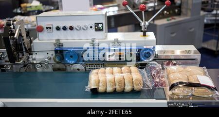 Confezionamento automatico della macchina impacchettatrice a cuscino per prodotti da forno. Macchina confezionatrice per pane, toast, panini e materie plastiche sulla linea di produzione di prodotti da forno Foto Stock