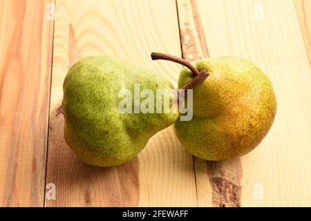 Due pere verdi naturali, primo piano, su un tavolo di legno. Foto Stock