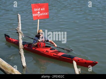 24 aprile 2021, Baviera, Rosenheim: Un kayak con un poster di protesta con l'iscrizione 'Schluss mit Verkehrtpolitik!' Proteste contro il Brennero-Nordzulauf nel Inntal pagaiando sul fiume Inn. Si tratta di un luogo in cui deve essere costruito un nuovo ponte ferroviario. Con forti proteste, una cosiddetta "ondata di rumore", le iniziative dei cittadini avevano lanciato in diversi luoghi della valle dell'Inn contro la prevista nuova costruzione di una linea ferroviaria a doppio binario attraverso la valle dell'Inn bavarese. Secondo gli organizzatori, tra le 4,500 e le 5,000 persone hanno preso parte alla protesta lungo il percorso previsto da Ostermün Foto Stock