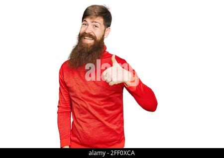 Uomo a testa rossa con barba lunga e abiti casual che fa un gesto felice con le dita. Espressione di approvazione guardando la fotocamera che mostra successo Foto Stock