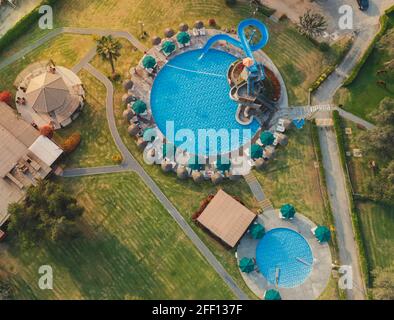 Vista aerea sulla piscina e sulle palme. Un luogo per il riposo e il relax. Ombrelloni da spiaggia. Beach club per il relax