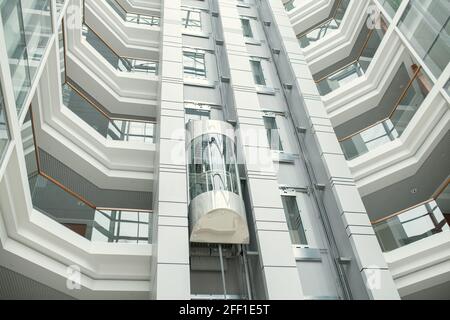 Ascensore vetroso nella lobby degli uffici a forma rotonda dal design contemporaneo e minimalista Foto Stock