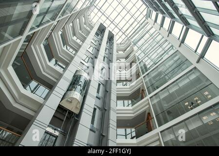 Interni moderni e rotondi per uffici con ascensore che si muove verso l'alto e vetroso muri Foto Stock