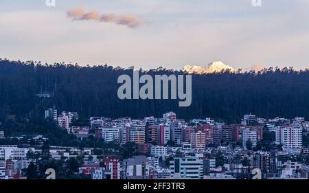 Panorama urbano di Quito al tramonto con appartamenti e vulcano Antisana, Ecuador. Foto Stock