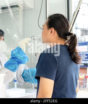 L'uomo asiatico è stato testato da personale medico in pressione ambiente negativa per il test covid-19 in campo esterno. Foto Stock