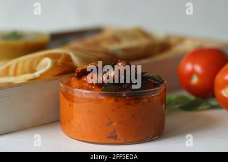 Frittella croccante a base di riso e lenticchie. Servito con un condimento fresco piccante e caldo fatto di pomodori e peperoncini rossi. Scatto su sfondo bianco. Foto Stock