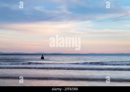 Un uomo di ferro soluto visto fuori dalla spiaggia a Crosby durante la marea alta al crepuscolo nell'aprile 2021. Fa parte di un altro luogo, l'installazione artistica sulla spiaggia di Crosby n. Foto Stock