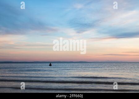 Un uomo di ferro soluto visto fuori dalla spiaggia a Crosby durante la marea alta al crepuscolo nell'aprile 2021. Fa parte di un altro luogo, l'installazione artistica sulla spiaggia di Crosby n. Foto Stock