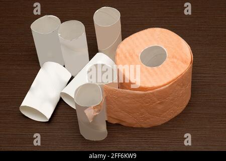 Rotoli di carta igienica usati con uno ancora in uso su tavolo di legno Foto Stock