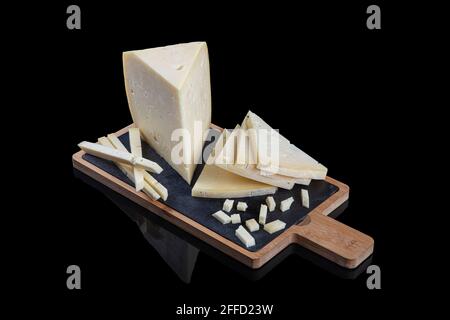 Un delizioso pezzo di formaggio cheddar al mercato. Sapori tradizionali per la colazione. Formaggio cheddar vecchio. Tradizionale formaggio vecchio isolato su sfondo nero Foto Stock