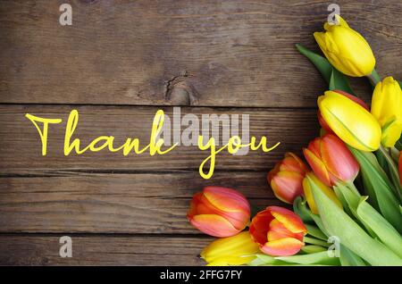 Grazie messaggio, tulipani colorati su sfondo di legno. Sfondo fiore primavera con tulipani fioriti, biglietto di auguri celebrazione. Festa della mamma. Foto Stock