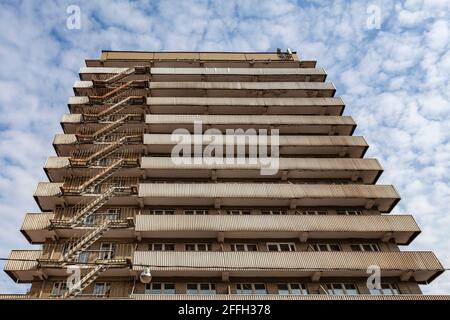 Facciata di un vecchio edificio a più piani con una scala in ferro che conduce tra i piani. Foto Stock