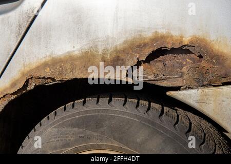 Corrosione della lamiera sulla ruota della vecchia auto bianca. Superficie arrugginita e disordinata. Grana sporca danneggiata dal sale della strada. Sfondo ruggine. Protezione di a Foto Stock