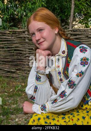 Salaj, Transilvania, Romania-14 maggio 2018: Bella giovane ragazza frettolata con capelli rossi e occhi blu in costume tradizionale rumeno folk in Marin Vil Foto Stock