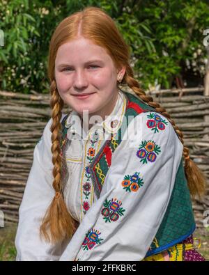 Salaj, Transilvania, Romania-14 maggio 2018: Bella giovane ragazza frettolata con capelli rossi e occhi blu in costume tradizionale rumeno folk in Marin Vil Foto Stock