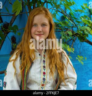 Salaj, Transilvania, Romania-14 maggio 2018: Bella giovane ragazza frettolata con capelli rossi e occhi blu in costume tradizionale rumeno folk in Marin Vil Foto Stock