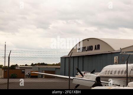 04-16-2021 Easton, Maryland, USA: Vista della sezione hangar dell'aeroporto locale di Easton (ESN) con un aereo ad elica parcheggiato di fronte ad un edificio t Foto Stock