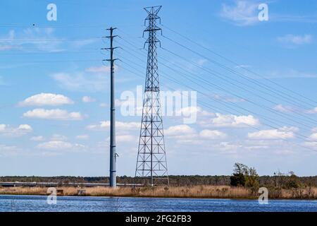 Una torre di trasmissione in acciaio alta per la trasmissione di elettricità ad alta tensione a lunga distanza. Situato in una posizione rurale presso un fiume con linee elettriche runniti Foto Stock