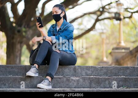 Giovane donna che usa il suo telefono cellulare all'aperto. Foto Stock